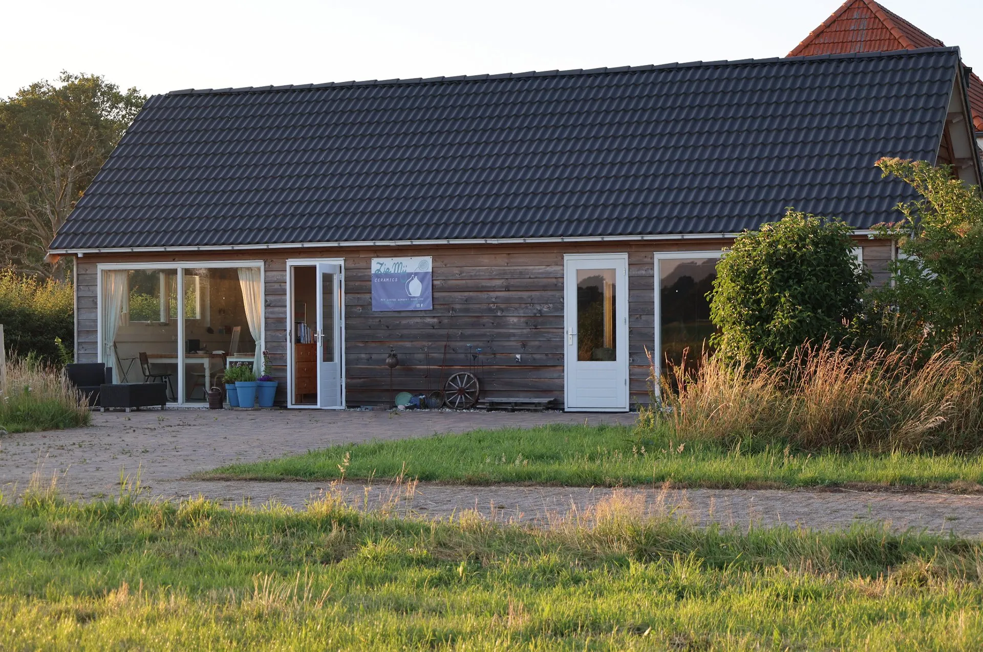 Het houten atelier in het groen, met de weilanden eromheen
